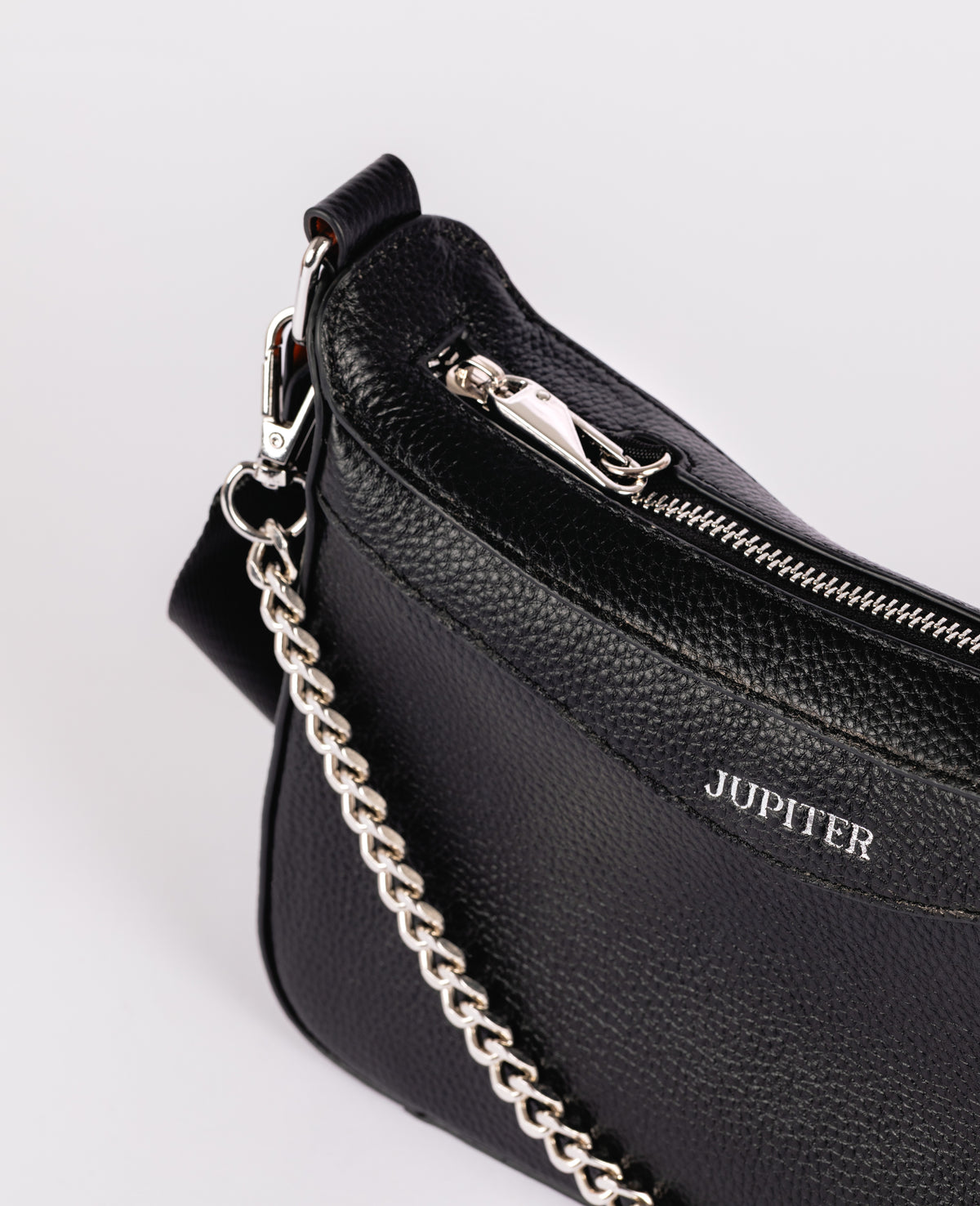 Close-up of a black pebbled leather travel handbag with a silver chain strap, silver zipper, and the brand name JUPITER printed in silver on the side, set against a light gray background.